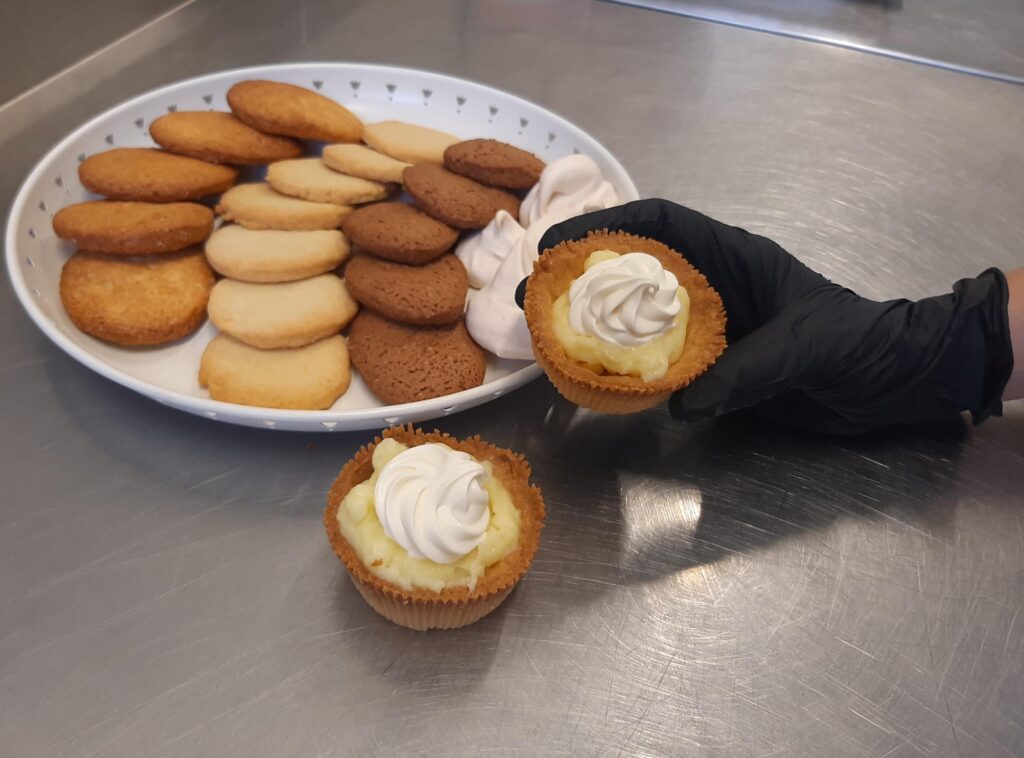 piatto con biscotti di diversi gusti e dolci con crema pasticcera e panna